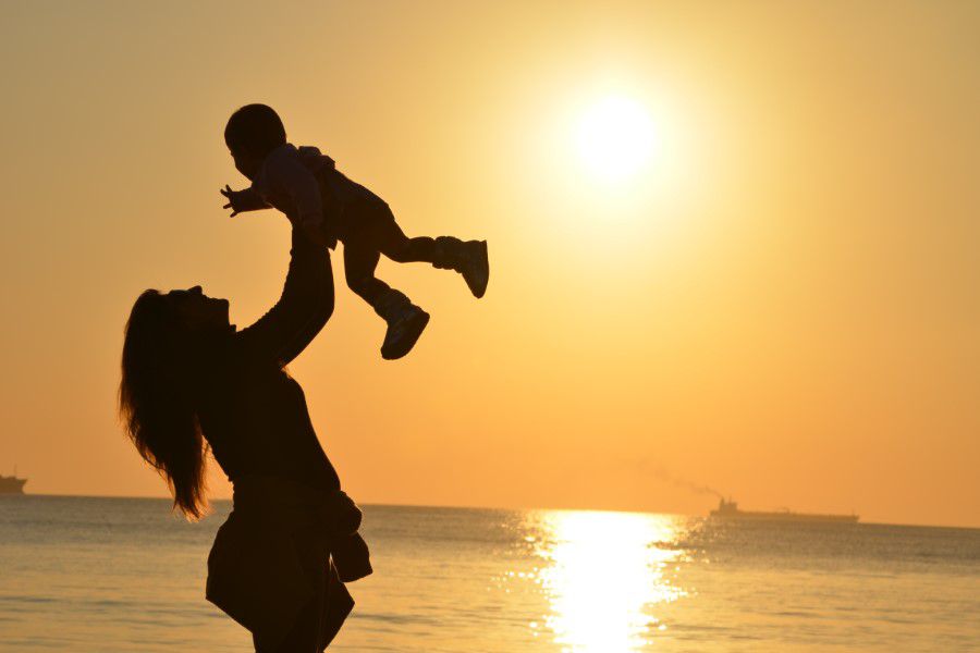 Mother holding baby in sunset